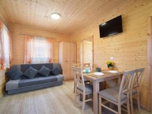 a living room with a couch and a table with chairs at Domki Pod Brzozami in Sarbinowo