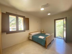 a bedroom with a bed and two windows at Posada Eco-Ostello di Buggerru in Buggerru