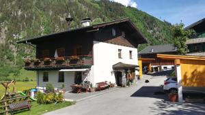 a white building with a black roof and a mountain at Kleintierhof Seidl-Eder in Rauris