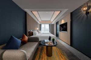a hotel room with a bed and a couch and a table at Delizzo Boutique Hotel Chengdu in Chengdu