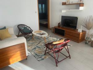een woonkamer met twee stoelen en een televisie bij Moon Flower, Pereybere in Grand Baie