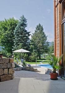 a patio with an umbrella and chairs and a pool at Wittelsbacher Hof in Oberstdorf