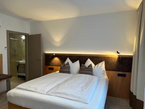 a bedroom with a bed with white sheets and pillows at Brauhotel Vitzthum in Uttendorf