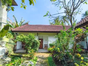 une petite maison blanche avec un toit rouge dans l'établissement The Semeton Homestay Senggigi RedPartner, à Montongbuwoh