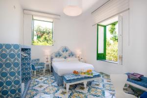 a bedroom with a bed and a table and two windows at Relais Correale Rooms & Garden in Sorrento