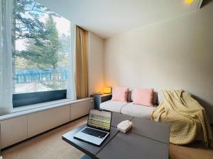 a living room with a couch and a laptop on a table at Tomamu Hostel in Shimukappu