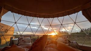 a room with a large glass window with the sunset at Bespoke Dome Perfect for a Couples Getaway in Tasmania in Sidmouth +5 photos