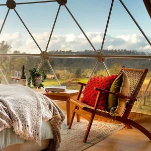 ein Bett und ein Stuhl in einem Zimmer mit Aussicht in der Unterkunft Incredible Dome Getaway on a Vineyard Perfect for Glamping, Tasmania in Sidmouth