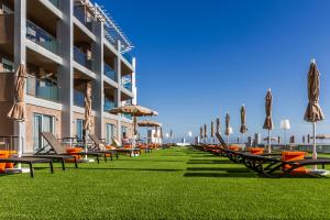 eine Reihe von Stühlen und Sonnenschirmen auf einem Rasen neben einem Gebäude in der Unterkunft Riviera Vista in Playa del Cura