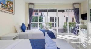 a living room with two beds and a large window at Evergreen Resort Cha-am in Cha Am