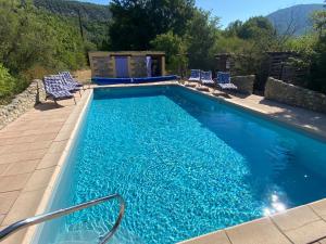 a large swimming pool with blue chairs at Maison Provençale avec piscine in Estoublon