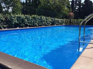 Ein Schwimmbecken mit blauem Wasser vor einer Hecke in der Unterkunft El Pendola in Fumane