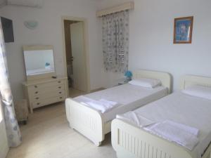 a bedroom with two beds and a dresser and a mirror at Paradisos House in Skiathos