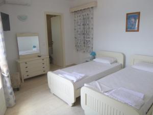 a bedroom with two beds and a dresser and a mirror at Paradisos House in Skiathos Town