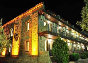 - un grand bâtiment en briques avec un balcon la nuit dans l'établissement Assos Park Hotel, à Assos