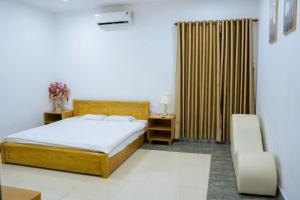 Un dormitorio con una cama y una silla y una ventana. en Avina Hotel Đắk Nông, 