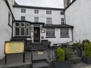 a white house with a sign in front of it at Lake District Pub with 10 en-suite rooms in Hawkshead