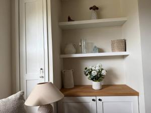 ein Raum mit einem Tisch mit einer Lampe und Blumen in der Unterkunft Maple Cottage in Bourton on the Water