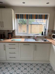 eine Küche mit Spüle und Fenster in der Unterkunft Maple Cottage in Bourton on the Water + 44 Fotos