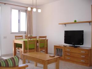 sala de estar con TV y mesa con sillas en Coblanca 8 - Zand Properties, en Benidorm