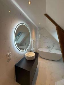 a bathroom with a sink and a tub and a mirror at Au coeur du chaos in Huelgoat +2 photos