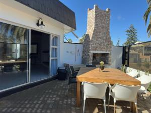 an outdoor patio with a wooden table and chairs at Poseidon Beachfront Holiday Home in Swakopmund