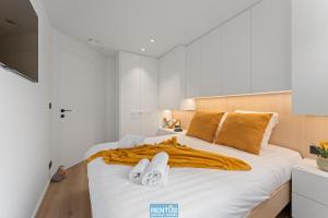ein Schlafzimmer mit einem Bett mit weißen Laken und orangefarbenen Decken in der Unterkunft Newport 2 - Luxury apartment near the sea in Nieuwpoort Bad in Nieuwpoort