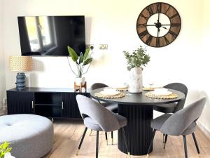 a dining room with a table and chairs and a clock at Newtown Hideaway in Boʼness