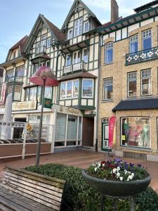 a building with a bench and an umbrella and flowers at Studio terrasse in Middelkerke