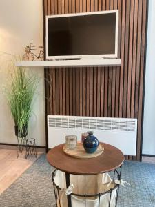 a living room with a table and a tv on a wall at Studio terrasse in Middelkerke
