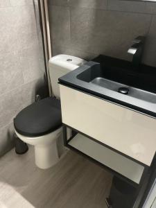 a bathroom with a toilet with a black lid next to a sink at Studio terrasse in Middelkerke