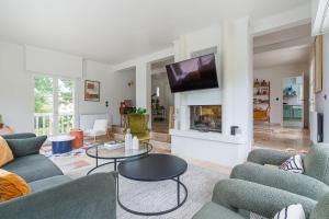 un soggiorno con divani blu e TV di Amazing Villa with Swimming Pool a Englesqueville-en-Auge