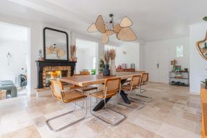 una sala da pranzo con tavolo, sedie e camino di Amazing Villa with Swimming Pool a Englesqueville-en-Auge