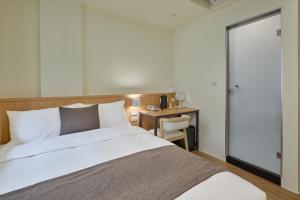 a bedroom with a bed and a table with a chair at Stay Easy lnn in Tainan