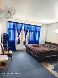a bedroom with blue curtains and a bed and a chair at Banphe​ Hostel in Ban Phe