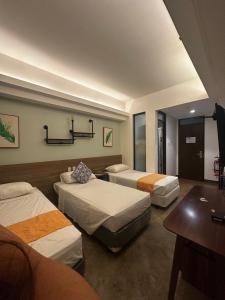a hotel room with three beds and a table at The Greenhive Hotel in Ibaan