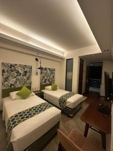 a hotel room with two beds and a television at The Greenhive Hotel in Ibaan