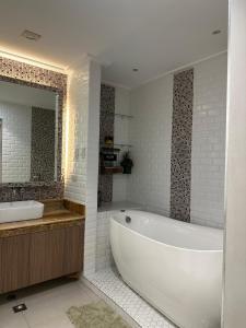 a white bathroom with a tub and a sink at The Greenhive Hotel in Ibaan