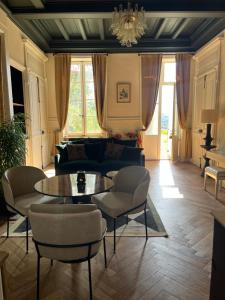 een woonkamer met een bank, een tafel en stoelen bij Appartement chic et de caractère ! in Saint-Cyr-au-Mont-dʼOr
