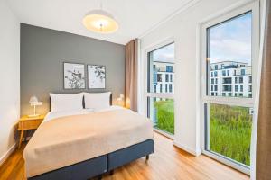 a bedroom with a bed and two large windows at Limehome Chemnitz Kirchgässchen in Chemnitz