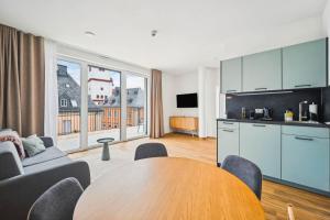 a living room with a wooden table and a kitchen at Limehome Chemnitz Kirchgässchen in Chemnitz