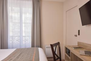 a bedroom with a bed and a desk with a laptop at Timhotel Le Louvre in Paris