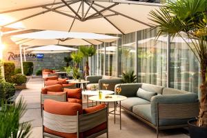 a restaurant with couches and tables and umbrellas at Radisson Blu Media Harbour Hotel, Düsseldorf in Düsseldorf
