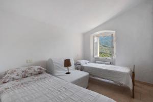 Una habitación blanca con dos camas y una ventana. en Casa Luciana Castelnuovo, en Castelnuovo Magra