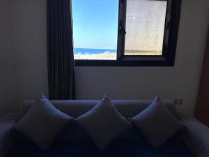 a couch with pillows in a room with a window at بيت العز للشقق الفندقية - علم الروم Bet Elezz Apartments-Alam Elrom in Marsa Matruh
