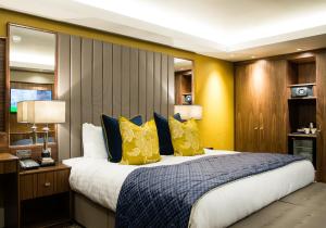 a bedroom with a large bed with yellow and blue pillows at Lea Marston Hotel in Lea Marston