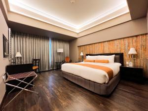 a hotel room with a large bed and a chair at The Bellevue Manila in Manila