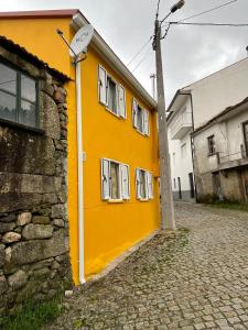 a yellow building with white windows on a street at Casa das bonecas in Castro Daire