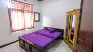 - un petit lit violet dans une chambre avec fenêtre dans l'établissement Hotel O Bougenville Resort, à Cianjur