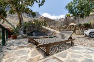 zwei Holzbänke auf einer Steinterrasse in der Unterkunft Casita Feliz - Casa Rural Tasarte by Villas Rivero in Tasarte